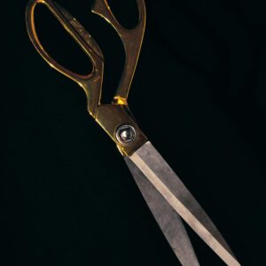 Stylish gold-handled scissors with sharp steel blades on a black backdrop, perfect for crafting themes.
