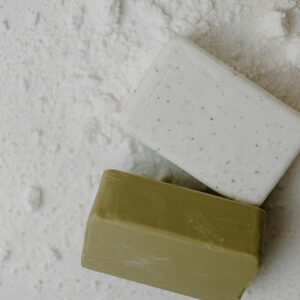 Close-up of two natural bar soaps on a white powdered surface, emphasizing hygiene.