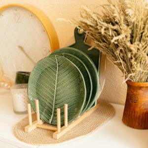A stylish arrangement of green leaf plates, a clock, and dried flowers, perfect for home decor inspiration.