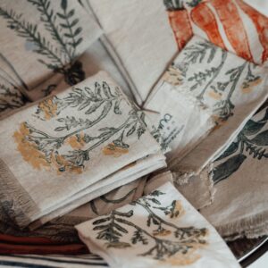 Collection of folded natural fabric napkins with flower and vegetable ornament with fringes on edges