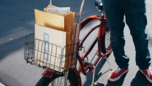 A bicycle with packages in the front basket on a sunny day, ready for delivery.