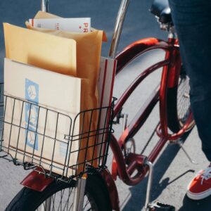A bicycle with packages in the front basket on a sunny day, ready for delivery.