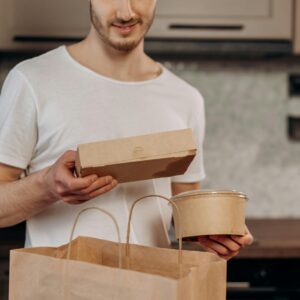A man in a white shirt manages takeaway food in a kitchen, emphasizing convenience and modern lifestyle.