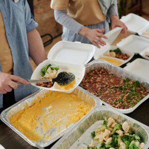 Volunteers preparing food packs indoors for donation.