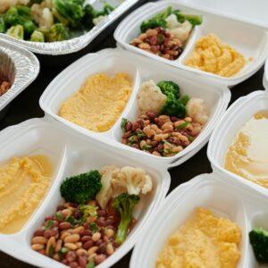 Assorted meal prep containers with beans, broccoli, and mashed potatoes, perfect for healthy eating.