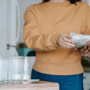 A couple carefully packing glassware in bubble wrap for a move, indoors.