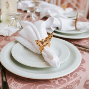 Sophisticated wedding table setting featuring butterfly napkin rings, fine china, and elegant tableware.