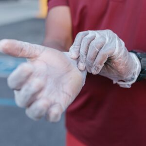 Person wearing transparent gloves, adding protection and hygiene outdoors.