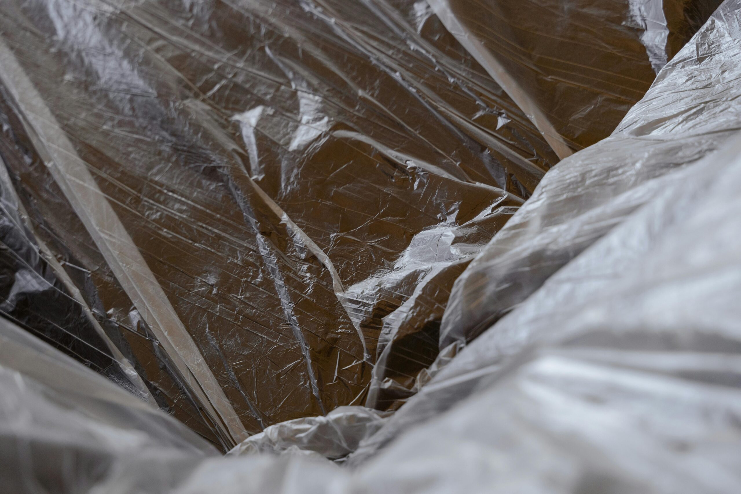 pexels photo 7414936 7414936 Close-up of transparent plastic sheeting over a wooden surface, revealing textures.