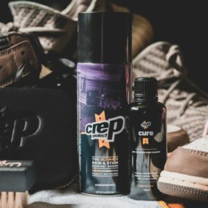 Closeup of set of various types of products for shoes care in bottles and brush for cleaning footwear from dust and dirt