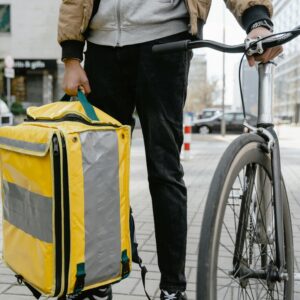 Food delivery cyclist in city holding a large thermal bag, ready for service.