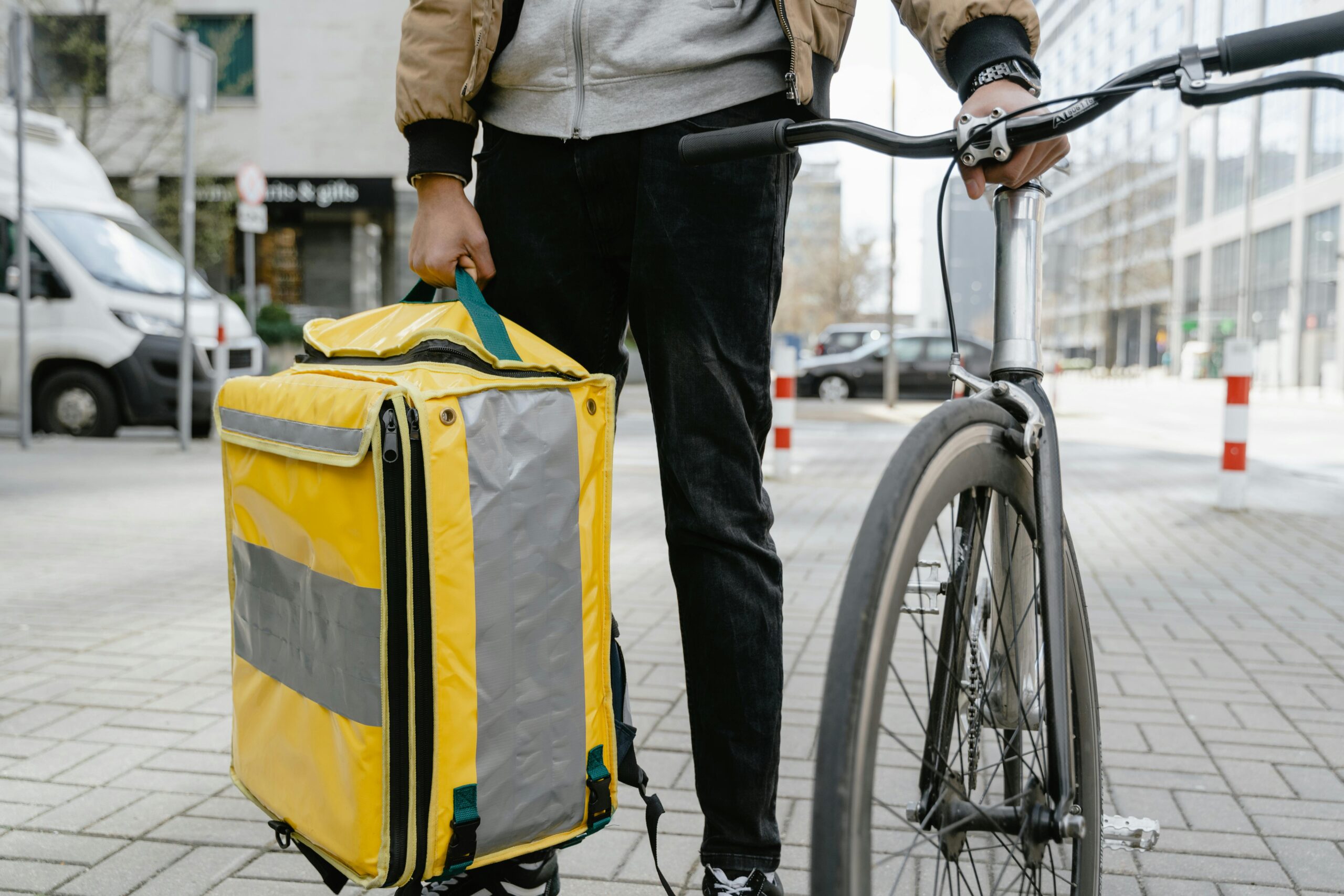 pexels photo 7706556 7706556 Food delivery cyclist in city holding a large thermal bag, ready for service.