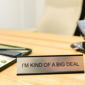 A desk sign with the phrase 'I'm Kind of a Big Deal' in an office setting, showcasing humor.