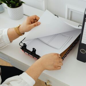 Business professional sorting through documents in a modern office setting.