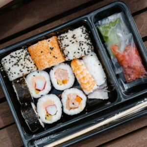Assorted sushi rolls beautifully arranged in a black bento box, perfect for a quick and tasty meal.
