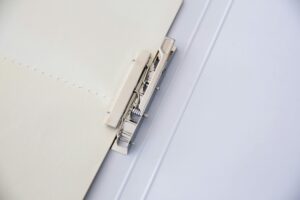 A metal binder fastens sheets of paper, offering a minimalist office solution.