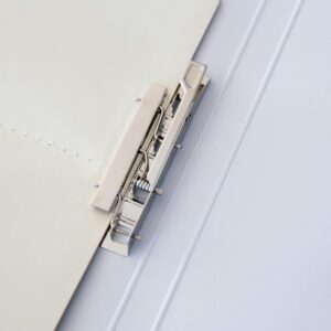 A metal binder fastens sheets of paper, offering a minimalist office solution.