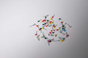 Scattered colorful push pins on a plain white surface, ideal for office and creative concepts.
