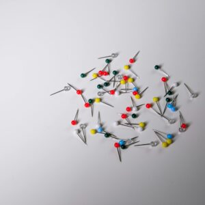 Scattered colorful push pins on a plain white surface, ideal for office and creative concepts.
