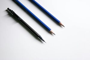 Close-up of a mechanical pencil and two wooden pencils on a white background.