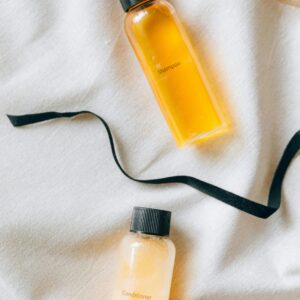 Flat lay of shampoo and conditioner bottles with a black ribbon on a textured fabric.