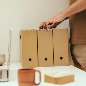 A person organizing files at a minimalist home office desk with a cup of coffee.