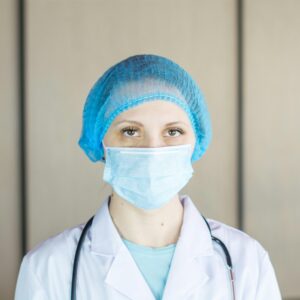 Close-up portrait of a healthcare professional wearing a mask and cap, showcasing safety and care.