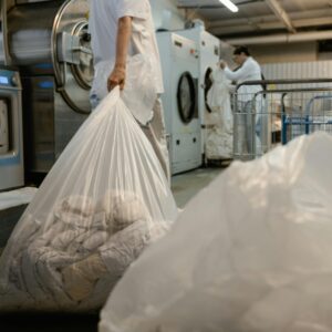 Person carrying laundry bag in a commercial laundry facility.