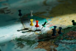 A close-up view of colorful push pins marking locations on a detailed world map.