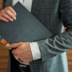 Businessperson in suit holding organized planner with tabs.
