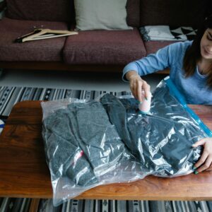 Woman sealing clothes in vacuum bags for efficient packing at home.