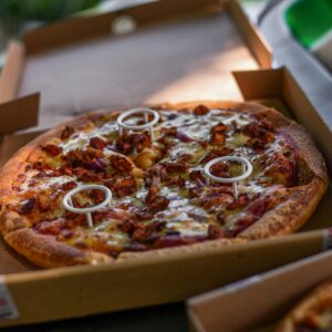 Close-up of a freshly baked pizza with toppings in a cardboard box, mouthwatering and ready to eat.